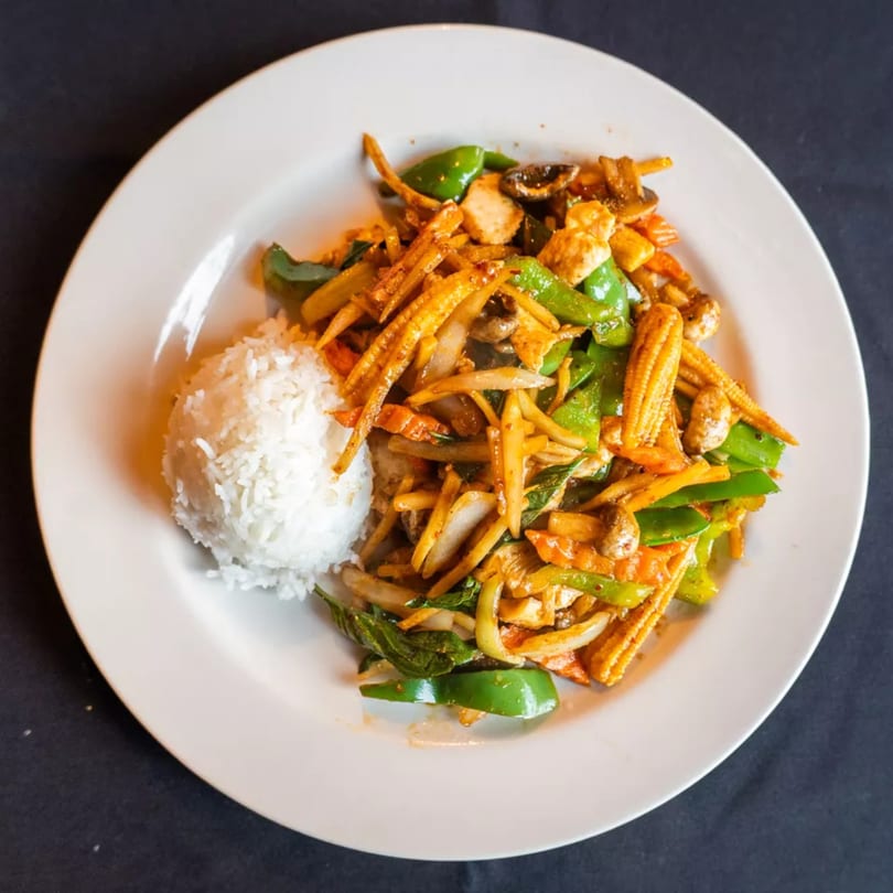 Stir-fried chicken with bell peppers, baby corn, and onions, served with white rice.